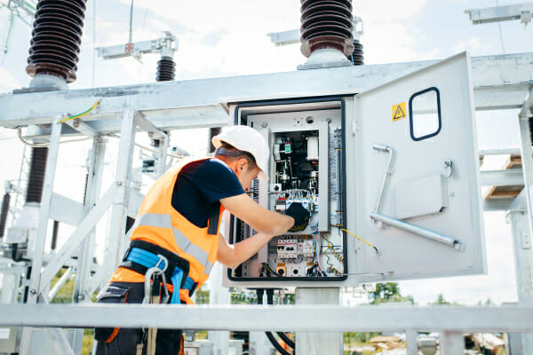 Technician inspecting substation electrical control panel